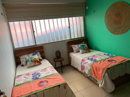 2 Betten in einem Zimmer mit grünen Wänden in der Unterkunft Casa 1090 ubicada cerca a todo. in Leticia