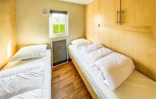 two beds in a small room with a window at Stunning Home In Tzummarum With Wifi in Tzummarum