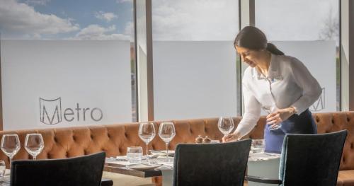 a woman standing in front of a table with wine glasses at Metro Apartments Dublin Airport in Dublin