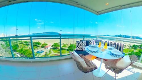 Un balcón con mesa y sillas y una gran ventana. en Book Santos - Unlimited 801 - Frente Mar de Verdade!, en Santos