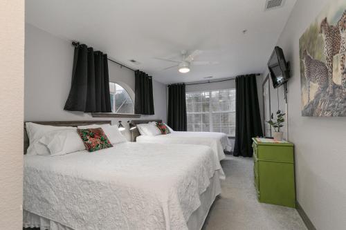 a bedroom with two beds and a tv and windows at 3BR Updated Condo - Family Games - Enclosed Patio - Stairs Required - FREE TICKETS INCLUDED - CH3-2 in Branson