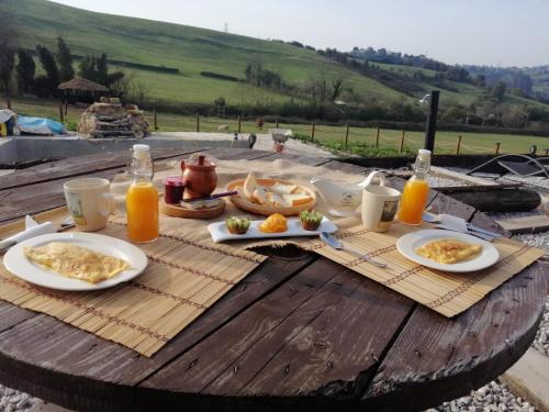 una mesa cubierta con platos de comida y zumo de naranja en Glamping Quintana, en Gijón