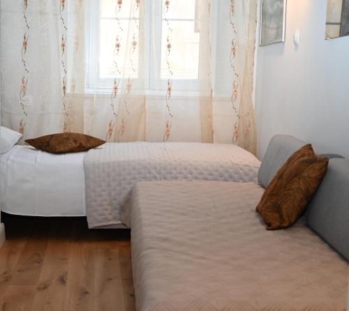 two beds in a room with a couch and a window at Old Town Apartment in Omiš