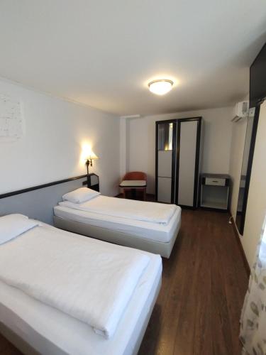 two beds in a hotel room with white sheets at studio in Sibiu