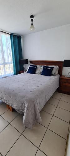 a bedroom with a large bed with blue pillows at PYB Souper Deptos in Santiago