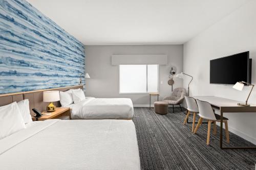 a hotel room with two beds and a desk at TownePlace Suites by Marriott Cape Canaveral Cocoa Beach in Cape Canaveral