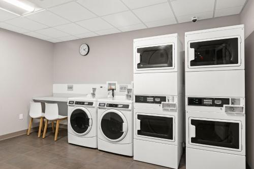 a laundry room with three machines and a table at TownePlace Suites by Marriott Cape Canaveral Cocoa Beach in Cape Canaveral