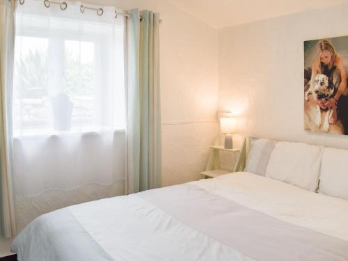 a bedroom with a white bed and a window at The Yard Beach Cottage - Uk43653 in Clynnog-fawr