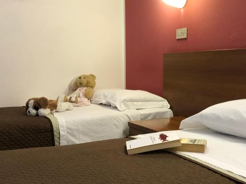 two teddy bears sitting on a bed in a hotel room at Hotel Kristall in Orvieto