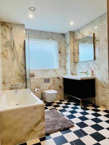 a bathroom with a tub and a toilet and a sink at Luxury 2 Bed 2 Bathroom apt near tube station! in London