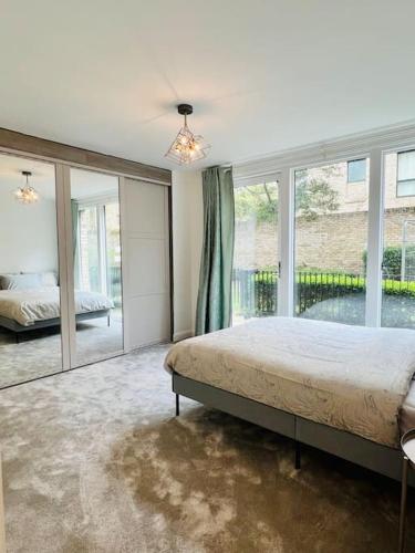a bedroom with a bed and a large window at Luxury 2 Bed 2 Bathroom apt near tube station! in London