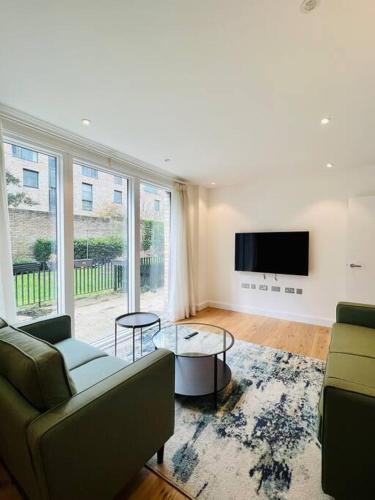 a living room with a couch and a tv at Luxury 2 Bed 2 Bathroom apt near tube station! in London