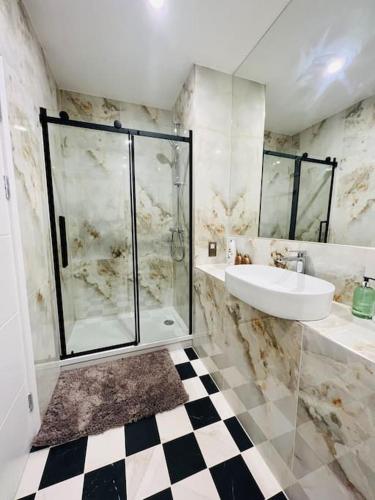 a bathroom with a glass shower and a sink at Luxury 2 Bed 2 Bathroom apt near tube station! in London