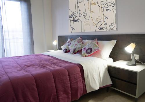 a bed with a purple blanket and pillows on it at PAPALi 289 in Catania