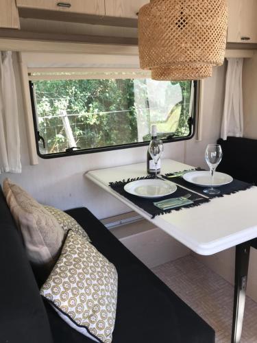 - une table à manger dans une petite caravane avec 2 verres à vin dans l'établissement La « Ravane », à Cysoing