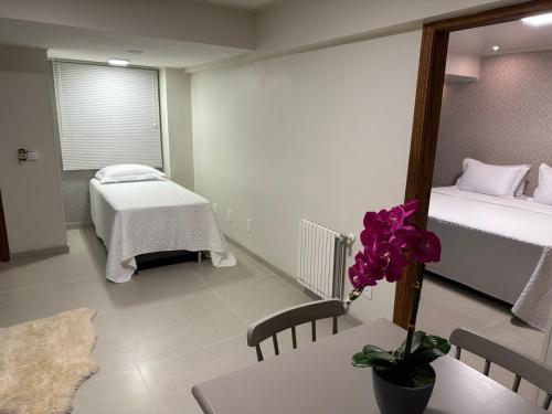 a room with two beds and a table with a flower on it at Pousada Villa Verde in Canela