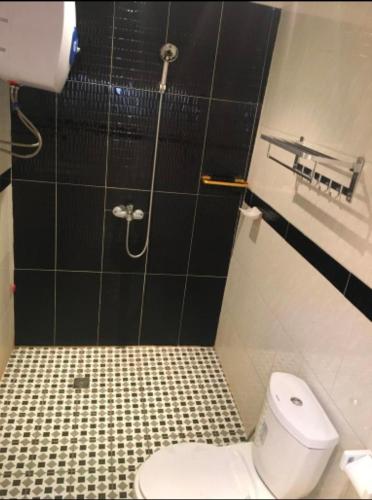 a bathroom with a toilet and a black tiled wall at Résidence le HAMEAU de BITENG in Yaoundé
