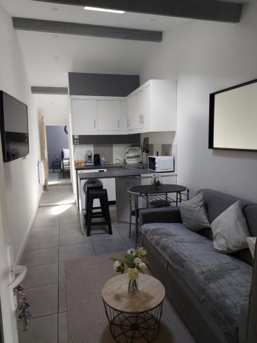un salon et une cuisine avec un canapé et une table dans l'établissement Maison annexe une chambre proche Paris, à Ecquevilly