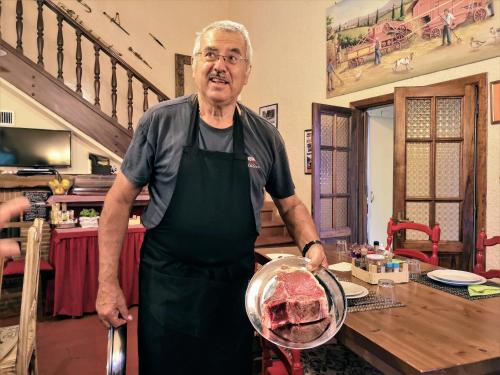 a man standing in a kitchen holding a piece of meat at Borgo Caiano Country Inn in Caiano