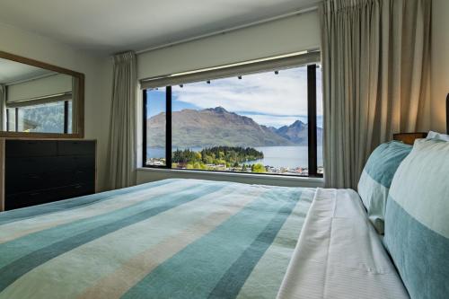 a bedroom with a large window with a view of the water at Magic mountain Vista in Queenstown