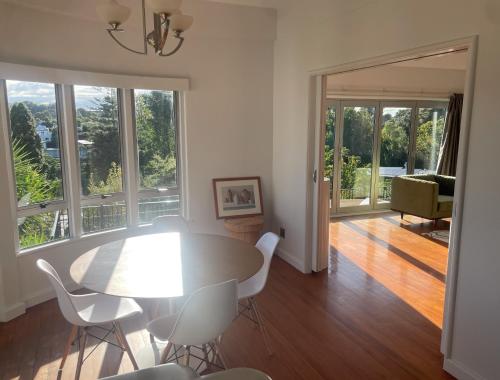 a dining room with a table and chairs and windows at CBD Apartment, River View in Hamilton
