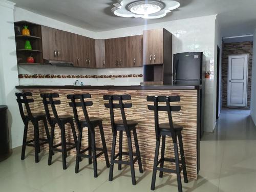 a kitchen with a bar with black bar stools at Kiosco Azul - Apartamento amoblado cerca al mar in Ríohacha