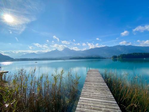a dock on a lake with mountains in the background at Seechalet Faaker See in Drobollach am Faakersee