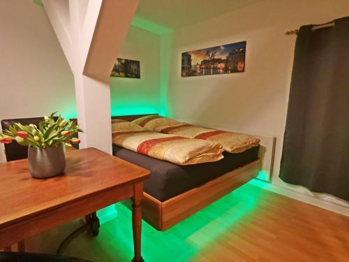 - une chambre avec un lit et une table avec des lumières vertes dans l'établissement Musashi Apartment 2, à Weimar