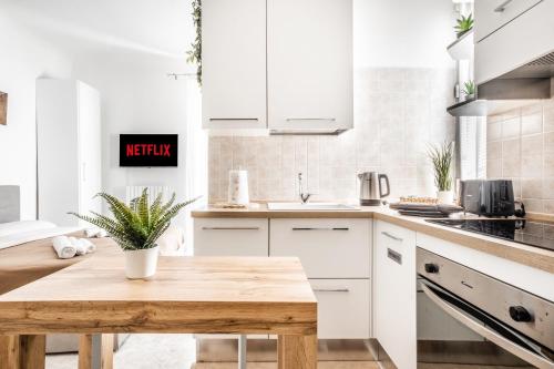 uma cozinha com armários brancos e uma mesa de madeira em [Pretty House Navigli-Duomo] Netflix & Design em Milão