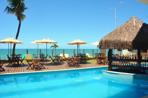 a swimming pool with chairs and umbrellas and the ocean at Romântico com vista deslumbrante in Natal