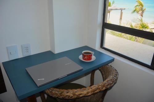 a blue desk with a laptop and a cup of coffee at Apto Romântico frente mar vista mar Elegance Flat in Natal