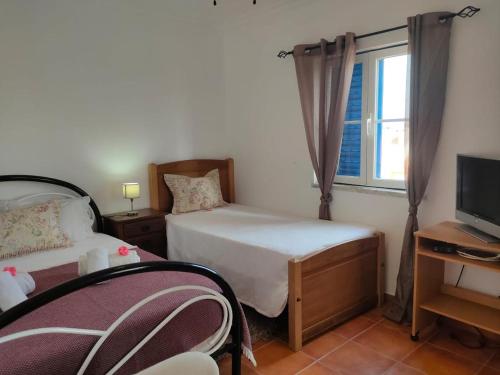 sypialnia z 2 łóżkami, telewizorem i oknem w obiekcie Casa Guerreiro w mieście Longueira