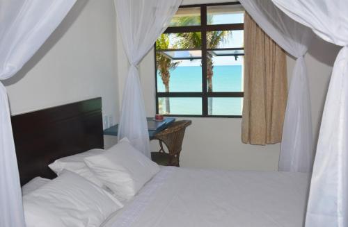 a bedroom with a bed with a view of the ocean at Apto Romântico frente mar vista mar Elegance Flat in Natal