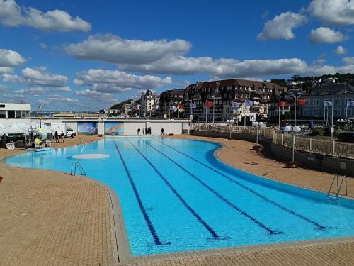 Une grande piscine bleue avec des personnes se promènent autour de celle-ci. dans l'établissement Appartement Trouville-sur-Mer vue mer imprenable, à Trouville-sur-Mer