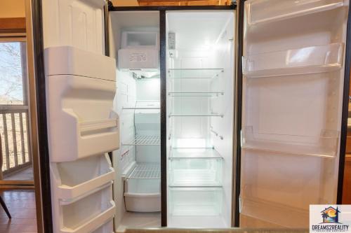 an empty refrigerator with its doors open in a kitchen at Forest Heights Lodge - 6BR - Pool Table - Near Silver Dollar City - FREE TICKETS INCLUDED in Branson
