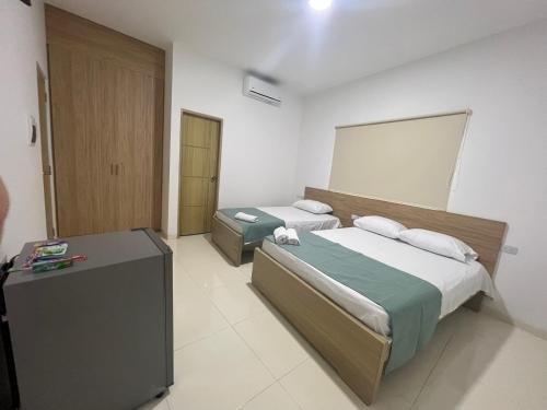 Cette chambre comprend deux lits et un bureau. dans l'établissement Hotel Mariscales Sincelejo, à Sincelejo
