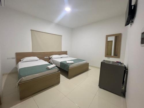 a room with two beds and a mirror in it at Hotel Mariscales Sincelejo in Sincelejo