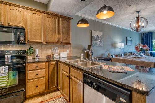 a kitchen with wooden cabinets and a sink at 2BR Condo - Dock for Fishing - Jacuzzi Tub - FREE TICKETS INCLUDED - MJ4-130 in Branson