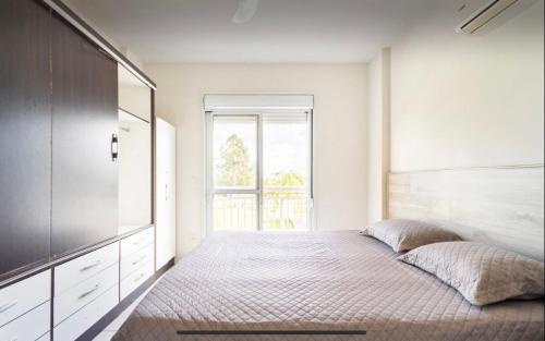 - une chambre avec un lit et une grande fenêtre dans l'établissement Apartamento Completo nos Ingleses, à Florianópolis