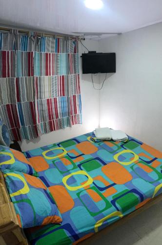 a bed with a colorful comforter in a room at Hotel Villa Lucy in Playa Ladrilleros