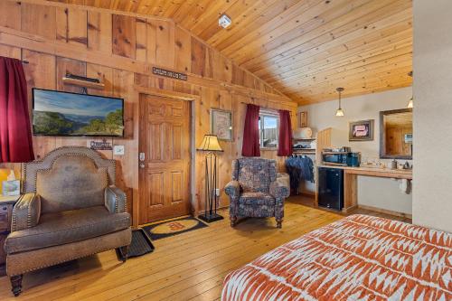 1 dormitorio con paredes de madera, 1 cama y 1 silla en Trapper's Rendezvous, en Williams