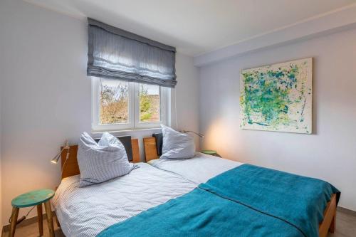- une chambre avec un lit avec une couverture bleue et 2 fenêtres dans l'établissement Strandhafer-Wulf-Weber, à Hohwacht