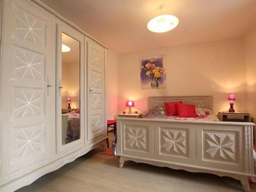 a bedroom with a bed with red pillows and a mirror at Gîte de charme en Auvergne, cour fermée, jardins privés, BBQ, babyfoot, proche St Jacques de Compostelle - FR-1-582-232 in Saint-Georges-Lagricol
