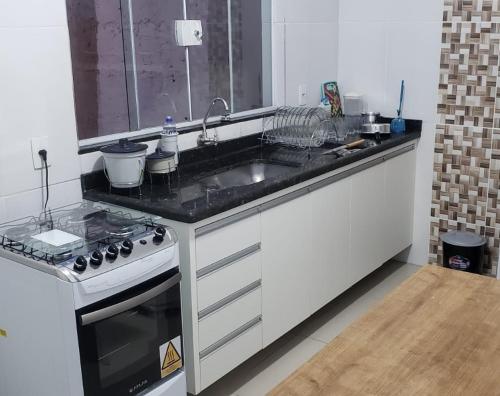 a kitchen with a sink and a stove at Apartamento Aparecida do norte in Aparecida