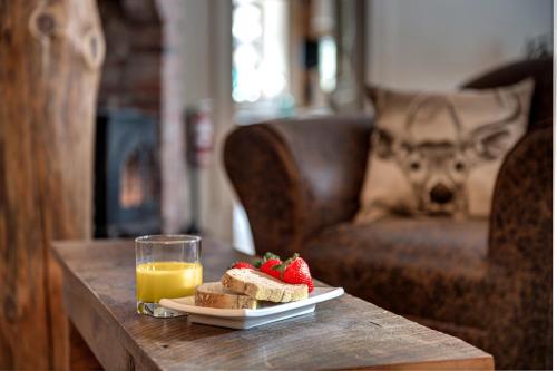 una mesa con un plato de pan y fresas y un vaso de zumo de naranja en Auberge le Cosy, en La Conception