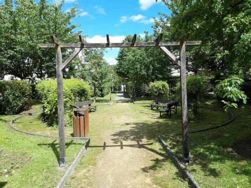 une pergola en bois dans un parc avec deux bancs dans l'établissement Spacieux Appart - 11 personnes - Disneyland & Paris, à Bussy-Saint-Georges