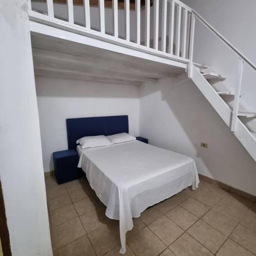 a white bed in a room with a staircase at Cómodo dormitorio con altillo in Fernando de la Mora