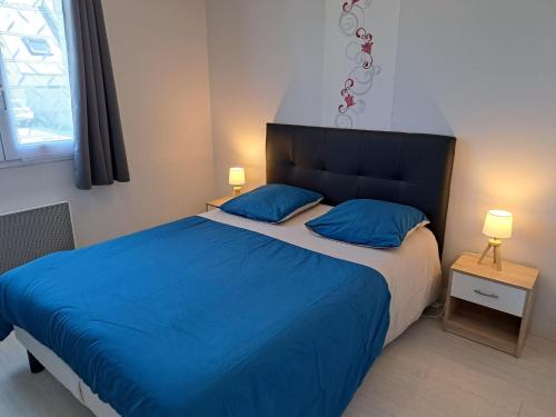 a bedroom with a blue bed with two blue pillows at Holiday Home in Guissény near Beaches in Guissény