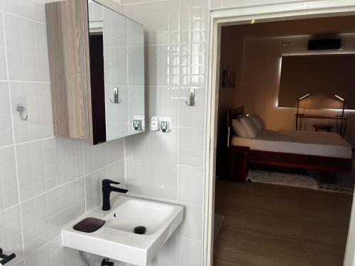 baño con lavabo y habitación con cama en Smart Stay Eco Friendly AirBnB, en Lusaka