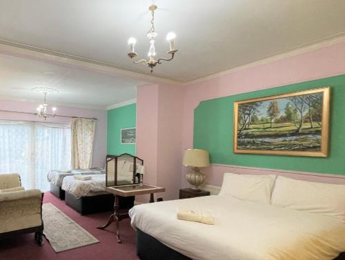 a hotel room with two beds and a chandelier at Lyttleton Lodge in Uxbridge